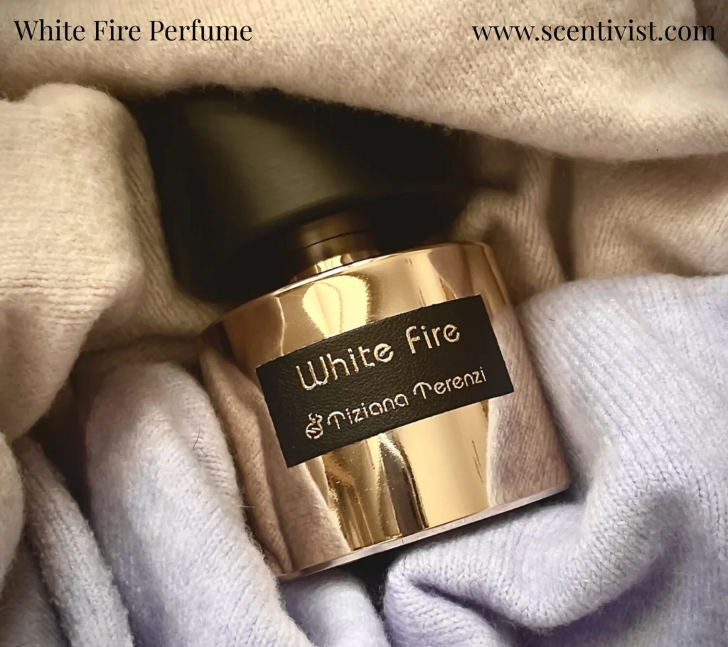 White Fire perfume by Tiziana Terenzi with a black cap placed on silky soft fabric, highlighting the luxurious gold bottle.