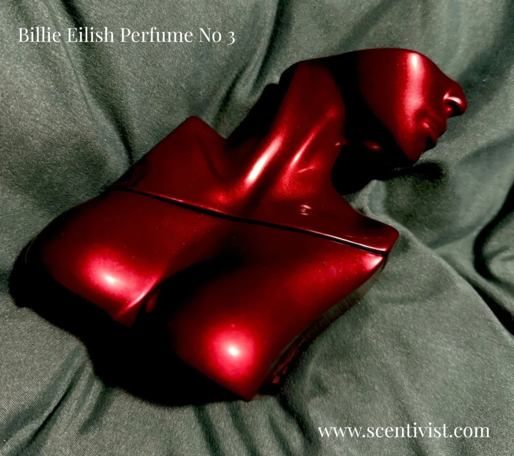 Billie Eilish Perfume No 3 sculpted bust perfume bottle resting on dark fabric.