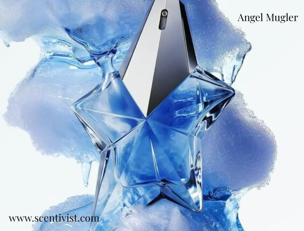 A blue, star-shaped Angel Mugler perfume bottle surrounded by splashes of icy blue liquid on a light background.