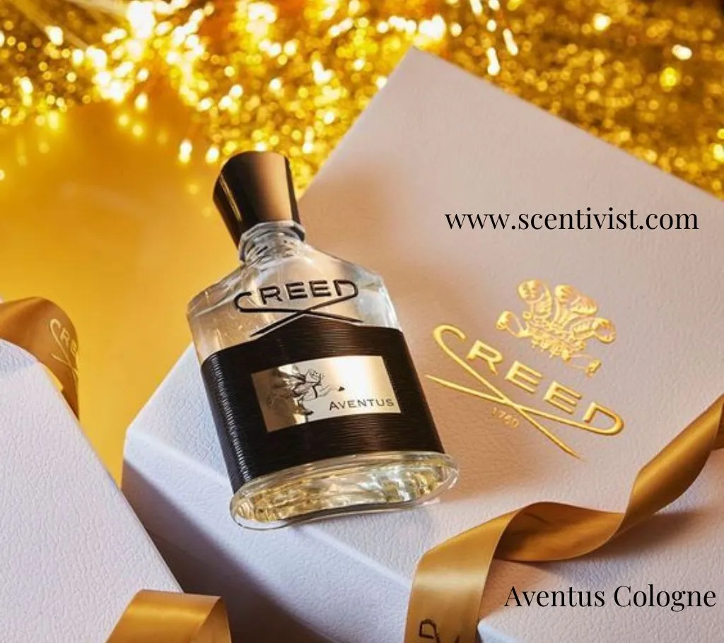 Elegant product image of Aventus Cologne by Creed perfume bottle placed on a white gift box with golden ribbons, beside a branded Creed card, set against a warm sparkling gold background.