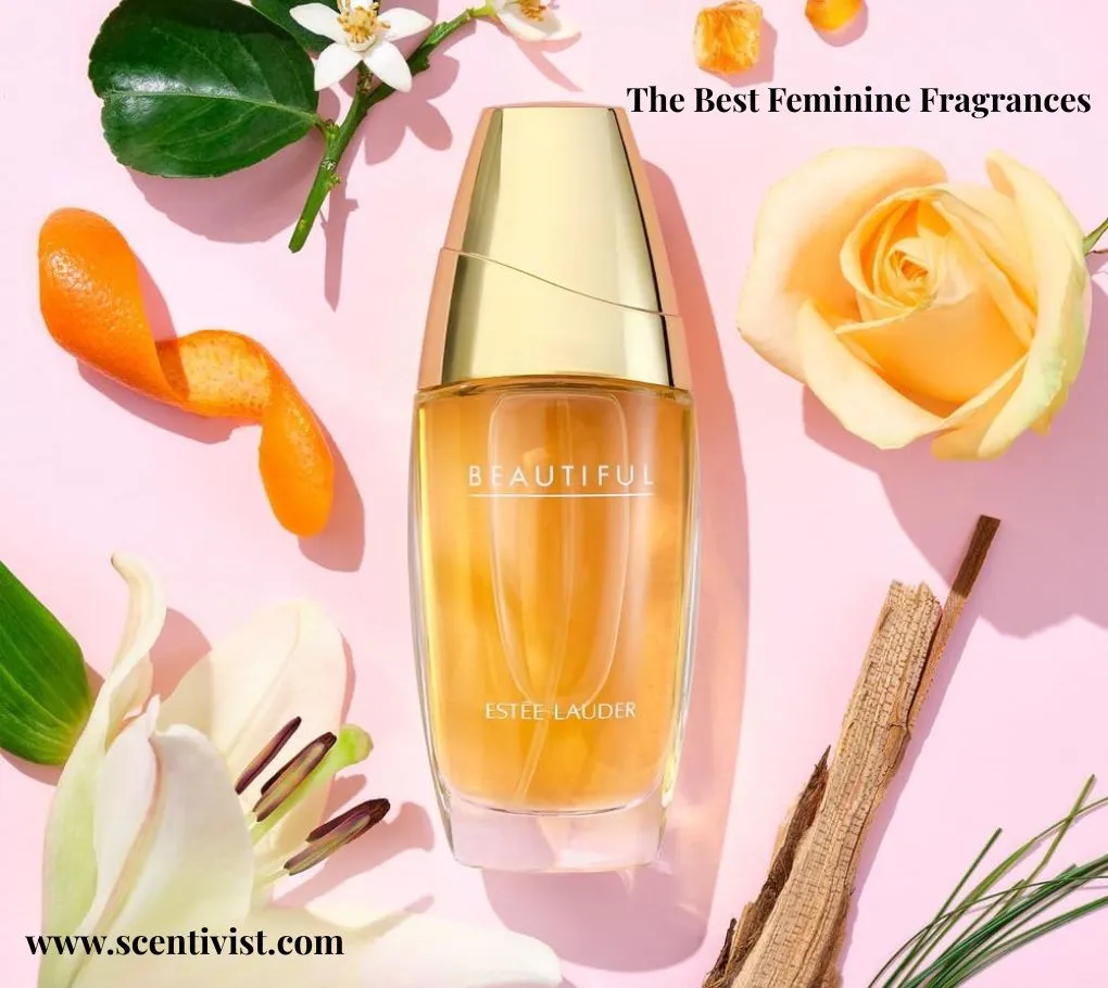 The best feminine fragrances; Estée Lauder Beautiful perfume bottle surrounded by flowers, citrus peel, and woody elements on a soft pink background.