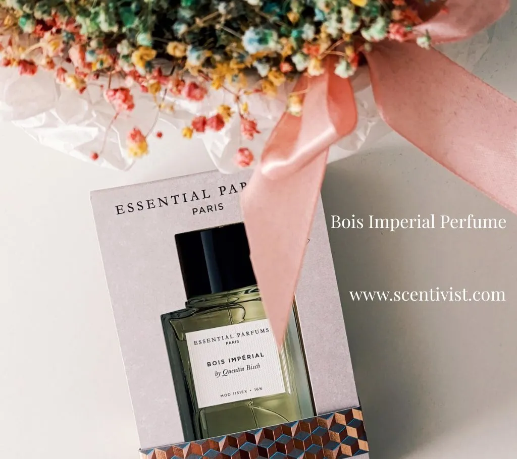 Bois Imperial by Essential Parfums perfume bottle placed beside a delicate bouquet of fresh flowers.