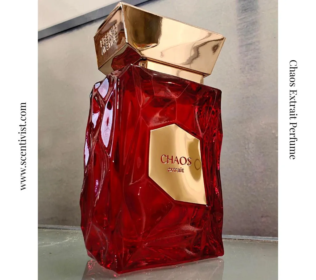 Chaos Men Perfume deep red crystal bottle with golden cap displayed among cherries, coffee beans, and greenery, highlighting its rich and bold fragrance character.