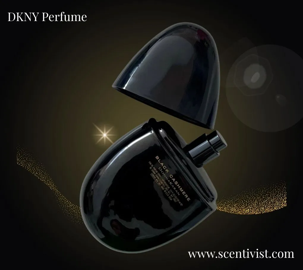 DKNY Black Cashmere perfume bottle with its cap lifted, set against a dark background with soft glowing accents.