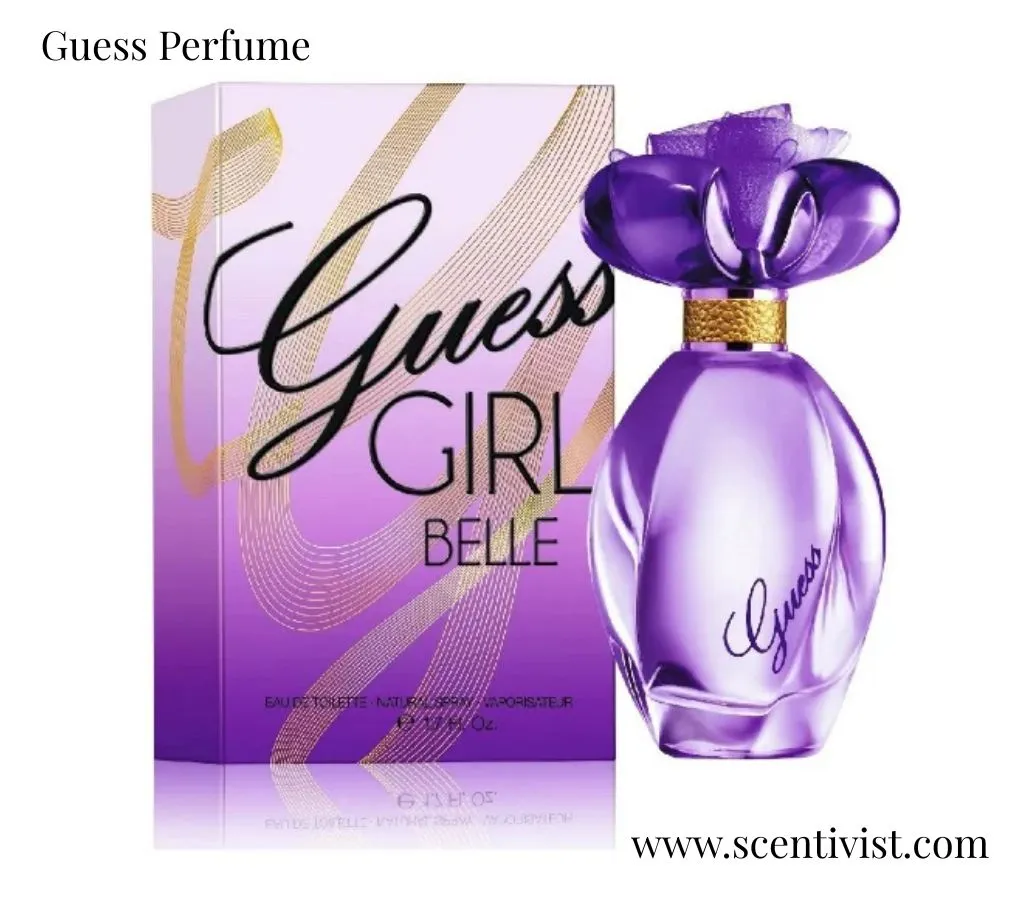 Guess Perfume Girl Belle bottle in purple glass with a flower-shaped cap displayed beside its matching purple and gold box.