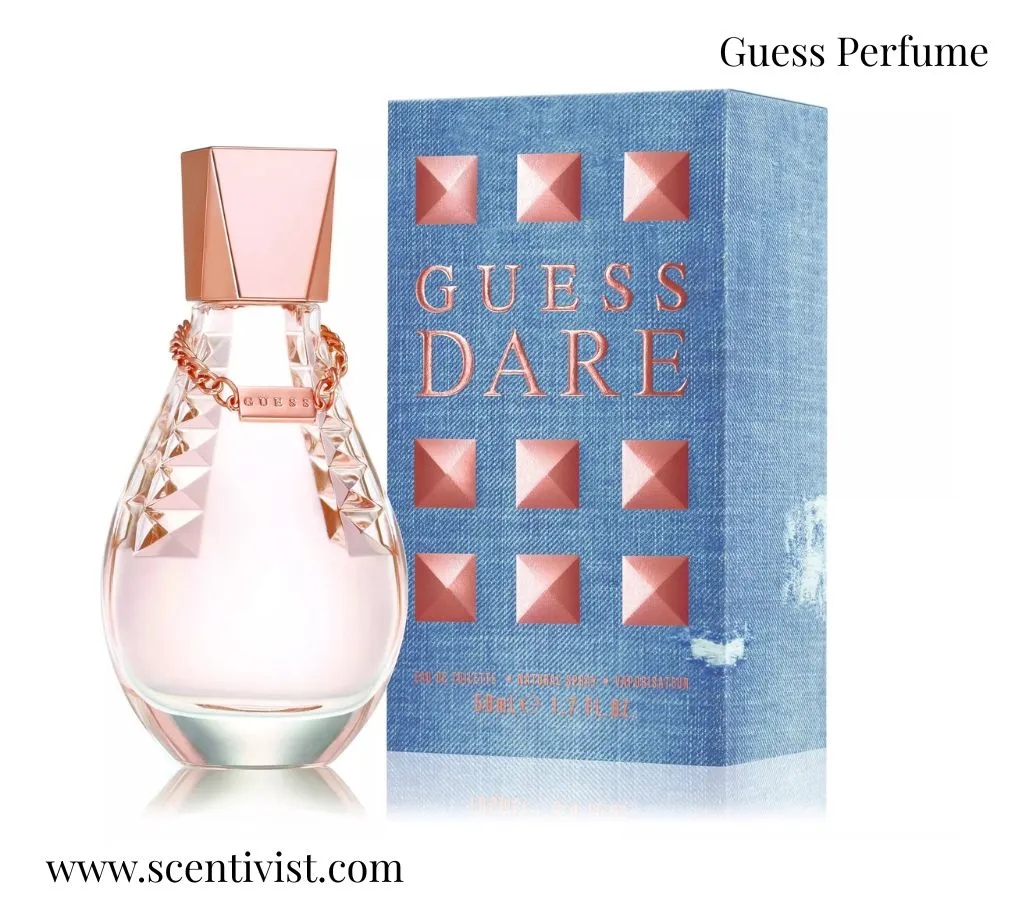 Guess Perfume Dare  bottle with a soft pink tone and rose gold cap displayed beside a blue textured box with studded design.