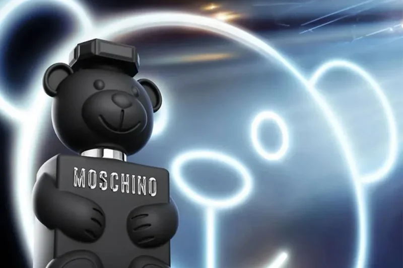 Moschino Perfume Toy Boy 2 bottle shaped like a black teddy bear against a glowing neon bear outline background.